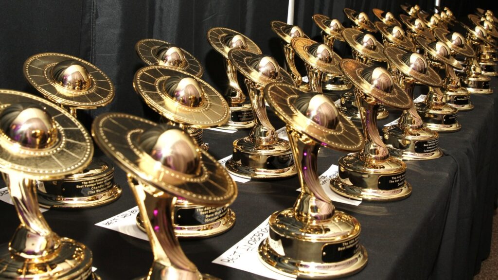 Saturn Awards, several rows of award statues, all bronze with a sculpt of the planet Saturn supported by an upward sweeping fluid pedistal.